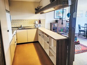 Une cuisine de taille réduite, équipée d’un évier, d’un plan de travail et de placards de rangement.