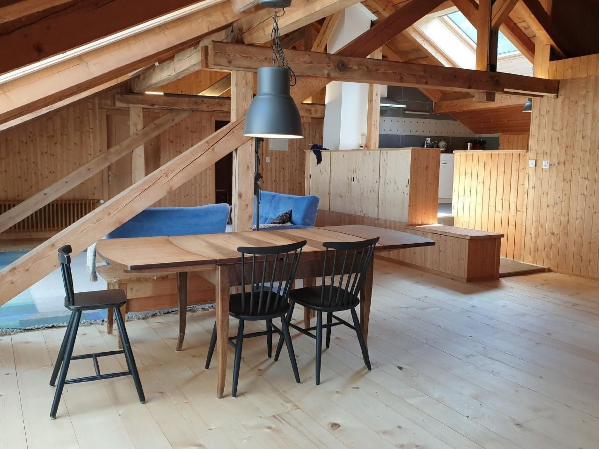 Un intérieur en bois comprenant une table à manger, des chaises, un canapé et un luminaire suspendu.