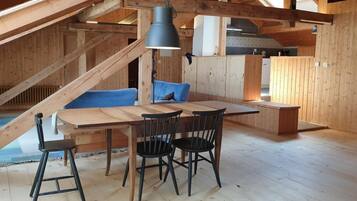 Un intérieur en bois comprenant une table à manger, des chaises, un canapé et un luminaire suspendu.