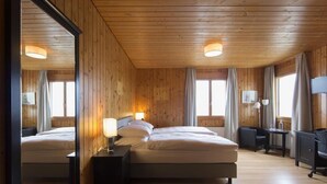 Ein Zimmer mit Holzwandverkleidung, zwei Betten, einem Schreibtisch und einem Fernseher.