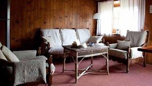 A cozy room with wooden walls, a sofa, two armchairs, and a small table.