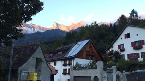 A traditional mountain village with stone buildings, a central square, and a mountain backdrop.