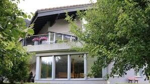 A modern two-story house with large windows, a balcony with flowers, and a well-maintained lawn. - "Ferienwohnung ""Spel Rein"" Cumpadials" by Interhome (Cumpadials)