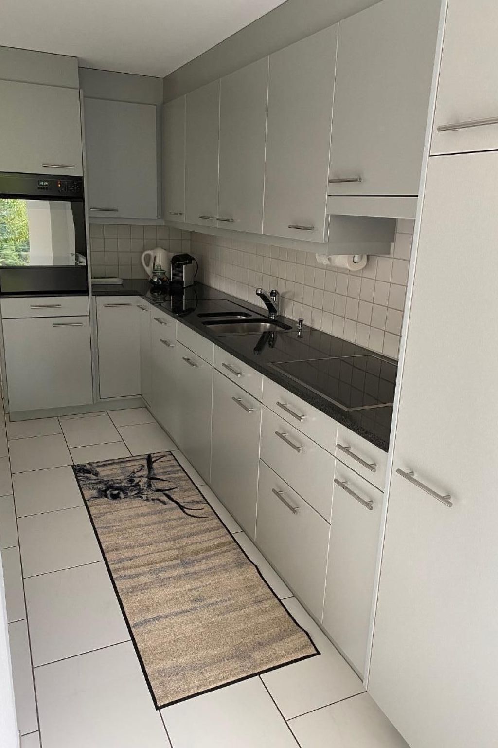 Een moderne keuken met witte kastjes, een zwart aanrecht en een roestvrijstalen spoelbak.