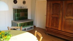 Un comedor con una mesa de madera, sillas, un armario verde grande y un guardarropa de madera.
