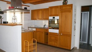 A kitchen with wooden cabinets, a built-in oven, and a stainless steel range hood. - Apartment Kat A by Interhome (Dürrenroth)