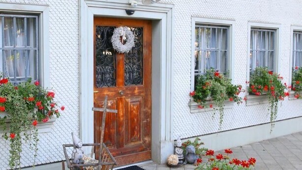 A white building with a wooden door, flower boxes on the windowsills, and a wooden cart outside. - Apartment Kat A by Interhome (Dürrenroth)