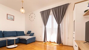 A modern living room with a sectional sofa, a small round table, a flat-screen TV, and a wooden floor. - Ceković 2 by Interhome (Krk/Šilo)