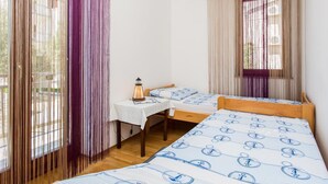 A small, clean room with two beds, a table, and a window with curtains. - Ceković 2 by Interhome (Krk/Šilo)