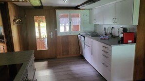 Een keuken met houten kastjes, een inbouwoven en een koffieapparaat.