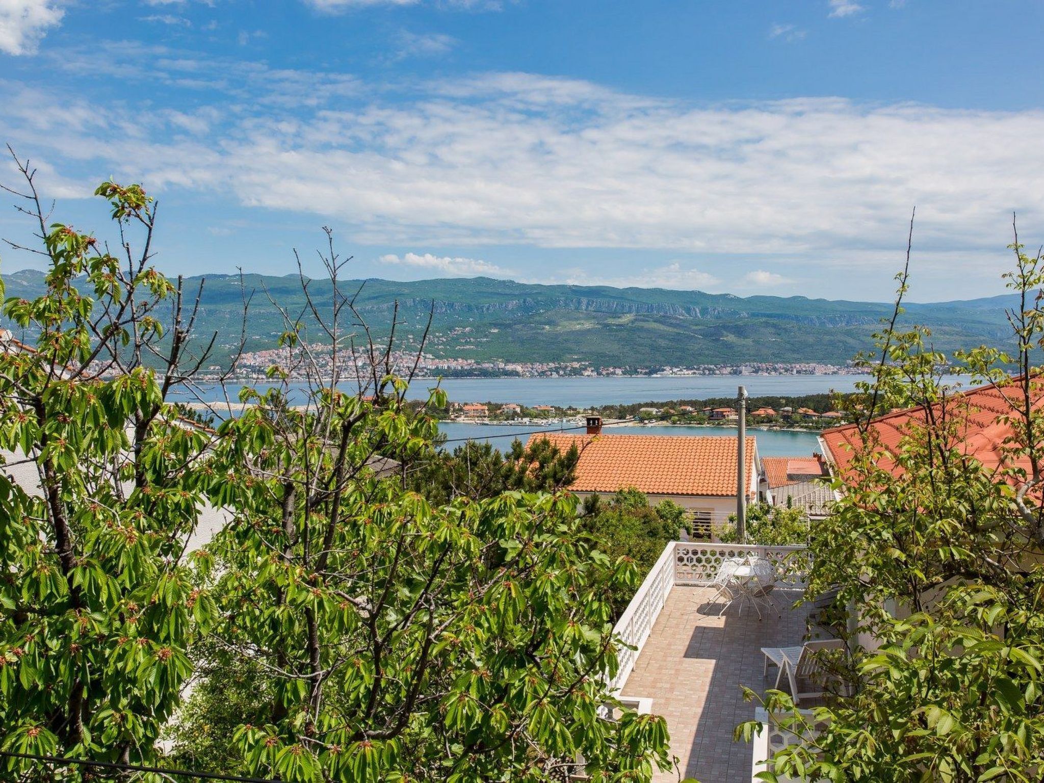 Blick auf eine Küstenstadt mit klarem Himmel, einem Gewässer und fernen Bergen.