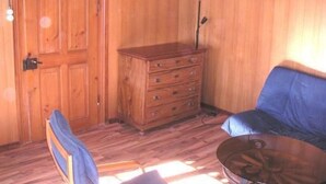 A wooden-paneled room with a blue sofa, a wooden dresser, and a small table. - Lamahof Tschäppel by Interhome (Huttwil)