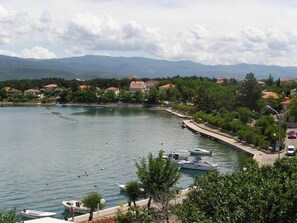 Eine Küstenlandschaft mit vertäuten Booten am Ufer, umgeben von Wohnhäusern und Grünflächen.