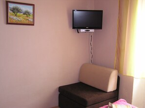 Een kamer met een eenpersoonsbed, een aan de muur bevestigde televisie en een schilderij.