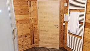 Une pièce aux murs lambrés, avec une porte, un radiateur et un porte-serviettes.