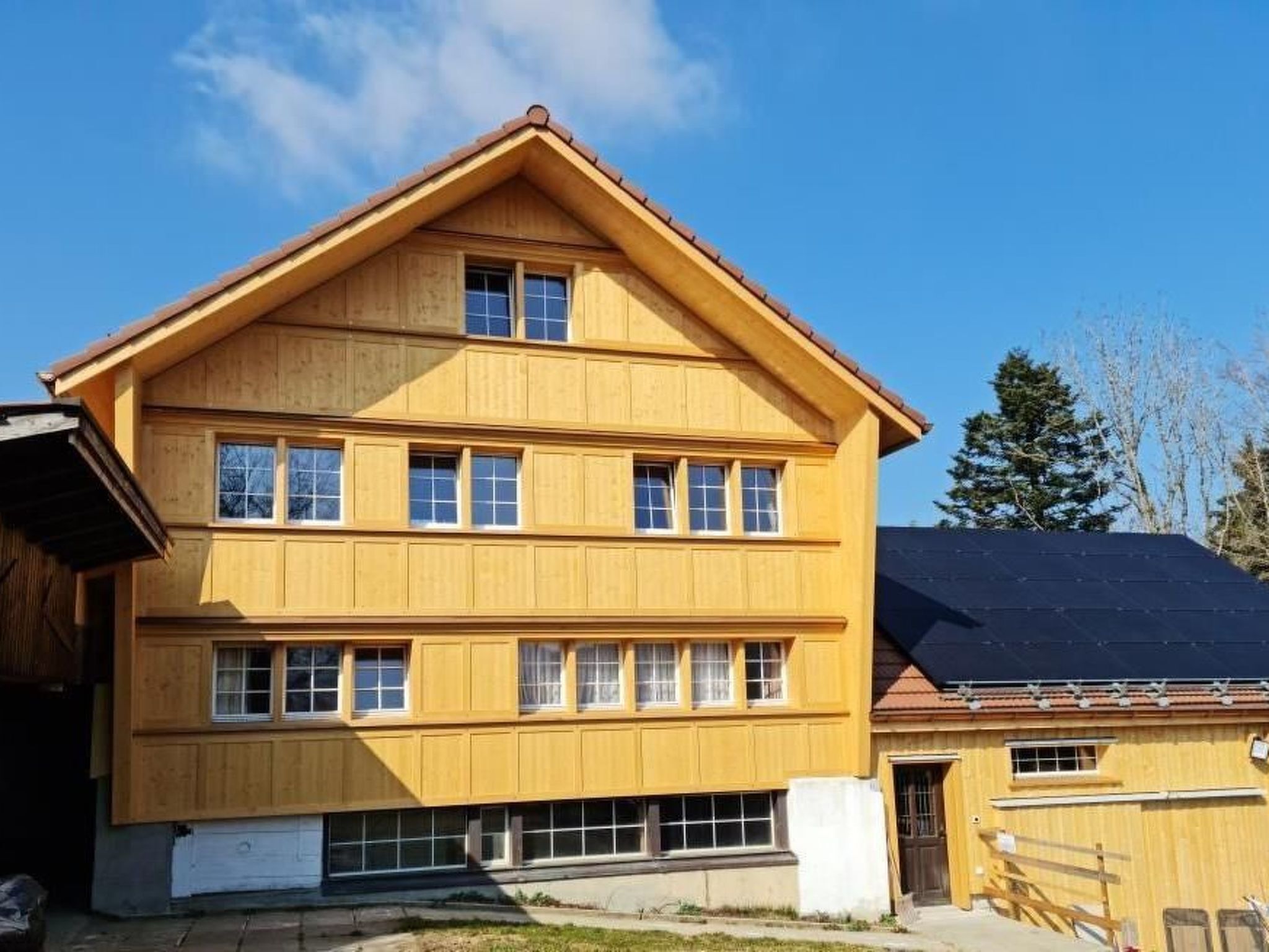 Un edificio de madera de varios pisos con techo a dos aguas y varias ventanas.