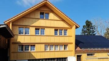 Un edificio de madera de varios pisos con techo a dos aguas y varias ventanas.