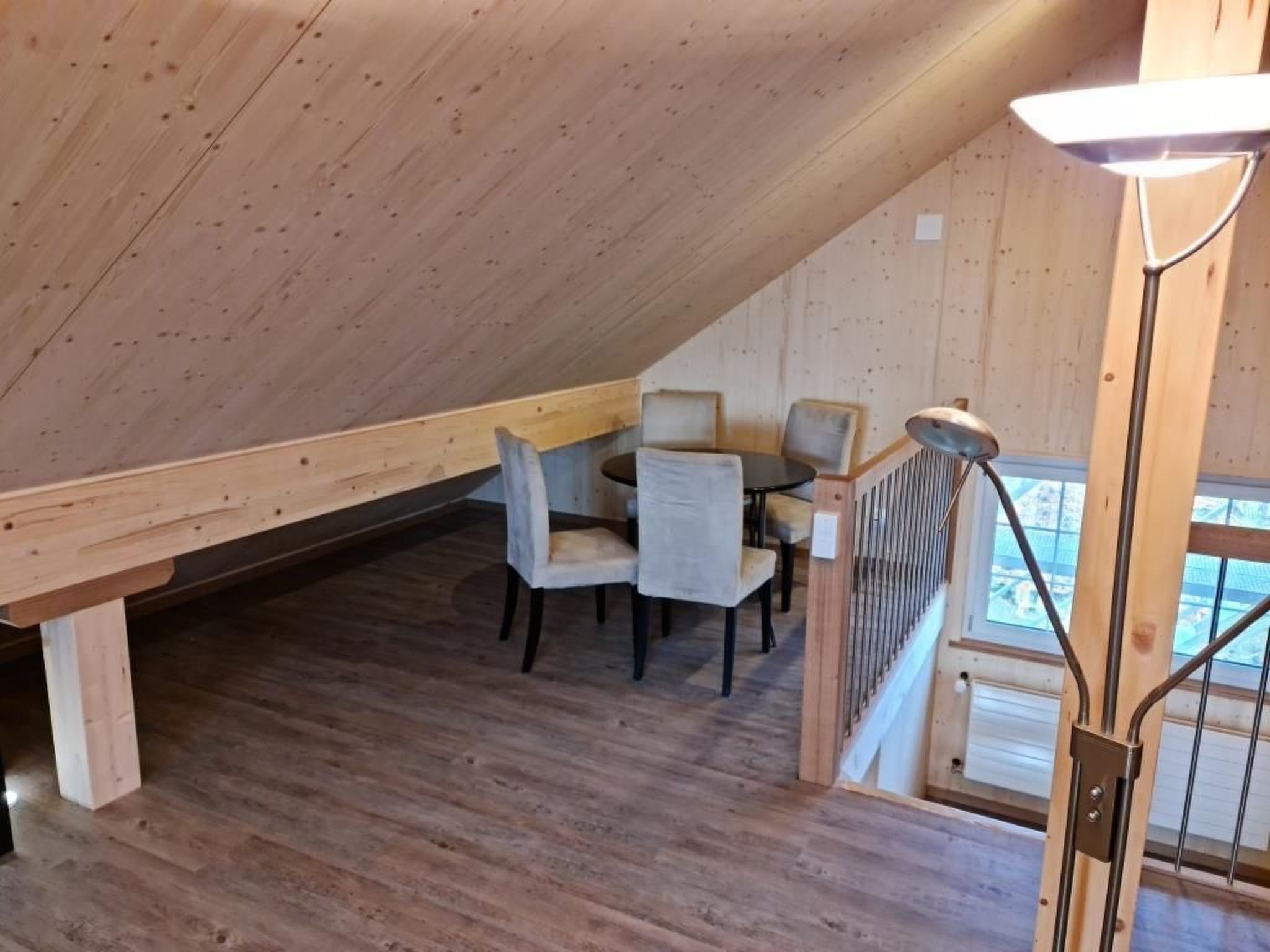 A wooden interior with a dining area, a staircase, and a view through a window.