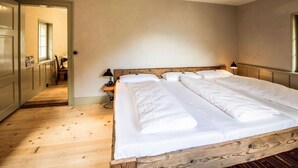Une chambre à coucher avec un grand lit, une tête de lit en bois et une petite table de chevet avec une lampe.
