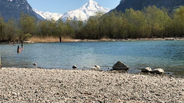 A river with a rocky shore and a backdrop of snow-capped mountains. - Ferienwohnung by Interhome (Attinghausen)