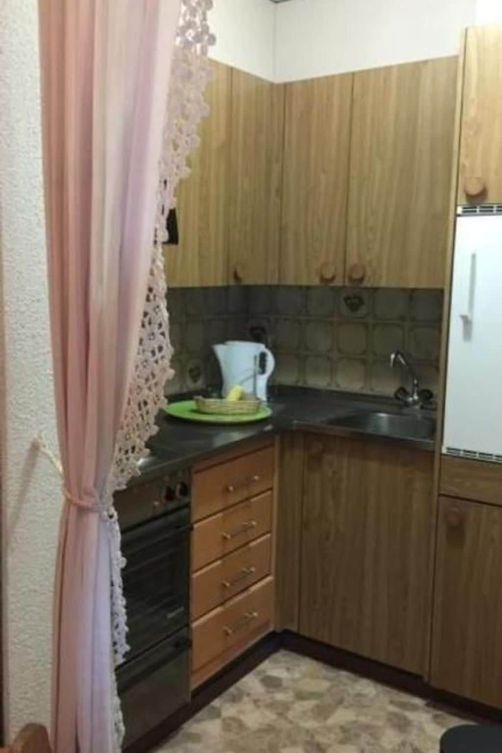 Una cocina pequeña con armarios de madera, un lavabo y un refrigerador.