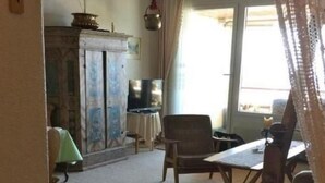 Een kamer met een houten tafel, een stoel, een televisie en een kast.