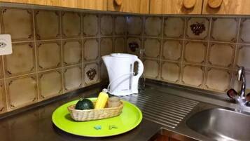 A kitchen with wooden cabinets, a stainless steel sink, and a green cutting board with vegetables.