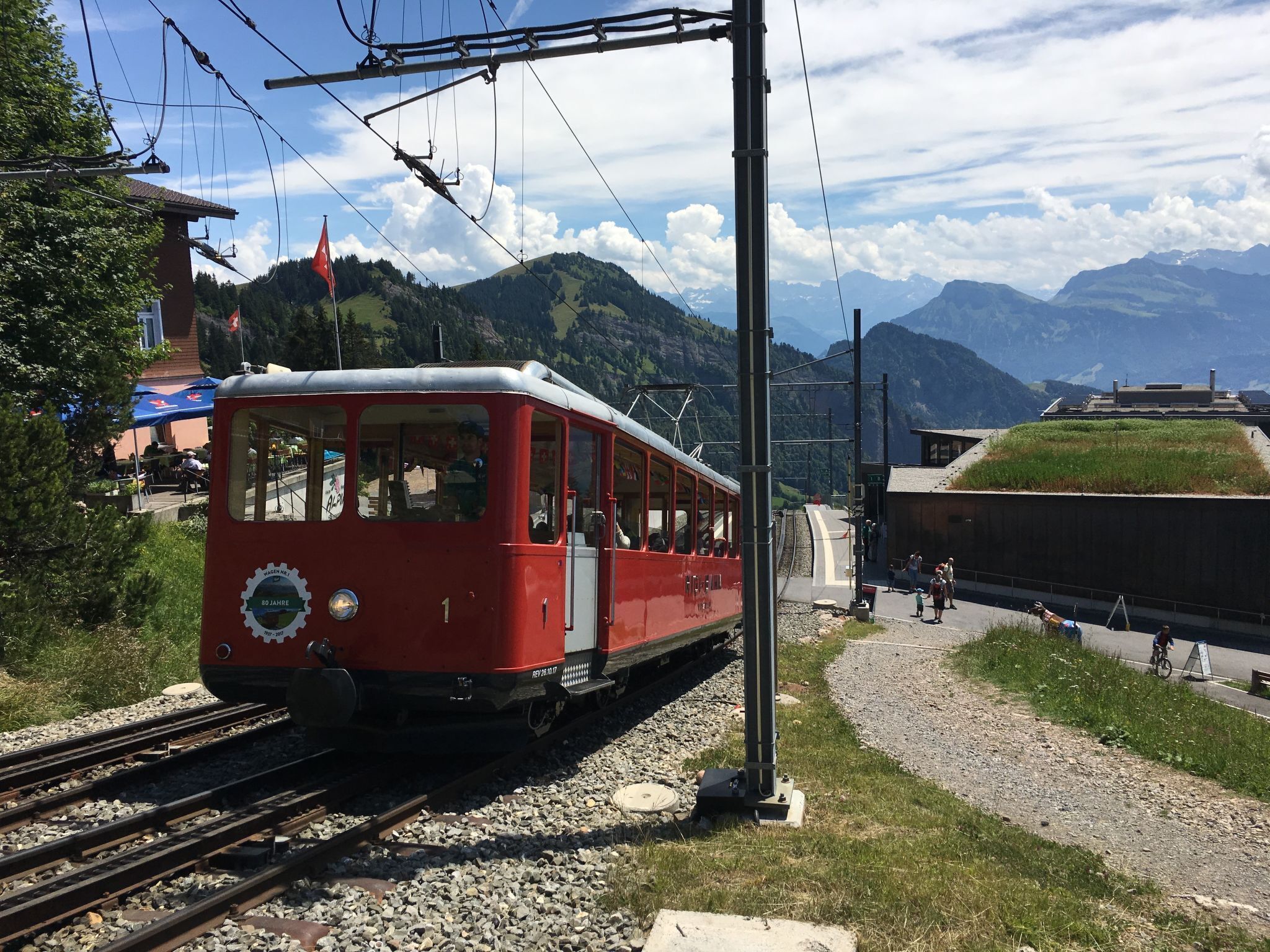 Eine rote, alte Straßenbahn auf Gleisen mit Bergen im Hintergrund.