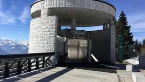Een rond gebouw met een stenen gevel, een bord met daarop 'Mineral Baths & Spa' en een uitzicht op besneeuwde bergen op de achtergrond.
