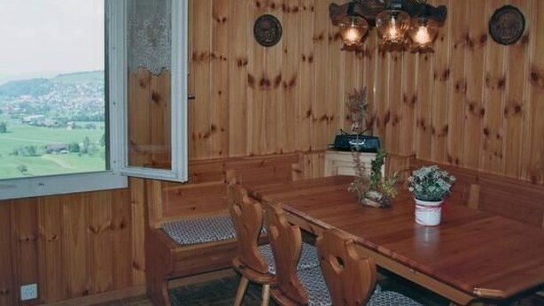 A wooden-paneled dining room with a large table, chairs, and a chandelier. - Fruehalp by Interhome (Unterägeri)