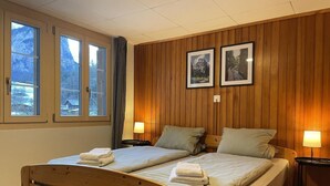 Un lit double avec une tête de lit et un pied de lit en bois, deux tables de chevet avec des lampes, et deux tableaux encadrés accrochés au mur.