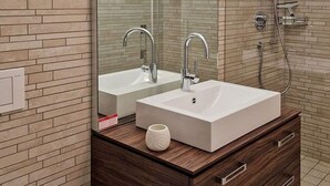 A modern bathroom with a white sink, two faucets, a mirror, and a shower. - Studio Flumserberg by Interhome (Flumserberg Tannenheim)