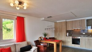 A modern kitchen with wooden cabinets and a dining area with a table and chairs. - Studio Flumserberg by Interhome (Flumserberg Tannenheim)