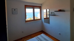 A room with a large window offering a view of the sea, a small shelf with a mirror, and a hanging light fixture. - mit Blick auf das Wasser by Interhome (Trogir)