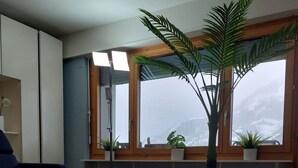 Ein modernes Wohnzimmer mit einem weißen Couchtisch, einem blauen Sofa und einem großen Fenster mit Blick auf eine verschneite Landschaft.
