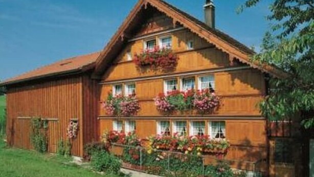 En traditionel træhus med mange vinduer og blomsterkasser på balkonen.
