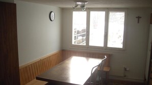 Une pièce avec un banc en bois, une table et une fenêtre donnant sur une ferme.