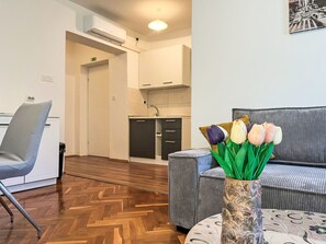 Eine moderne Hotellobby mit Sitzgelegenheit, einer Küchenzeile und einer dekorativen Vase mit Blumen.