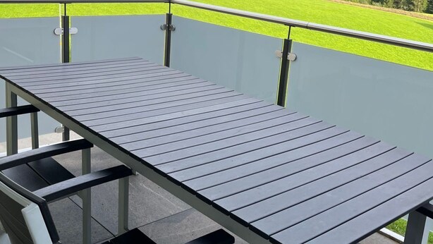 Eine Terrasse im Freien mit Tisch und Bänken, mit Blick auf eine grüne Landschaft und Berge.