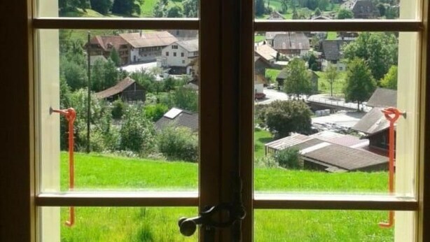A window with a view of a green landscape and buildings. - FeWo Südhang by Interhome (Rüschegg Heubach)