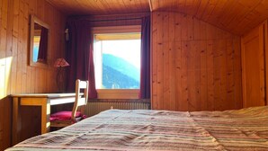Ein Zimmer in einer Holzhütte mit einem Bett, einem Schreibtisch und einem Stuhl.
