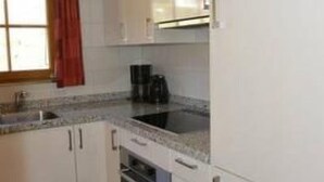 A compact kitchen with white cabinets, a built-in oven, and a coffee maker.