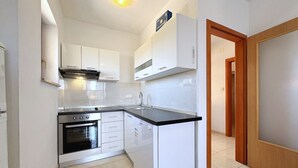 Una cocina moderna con armarios blancos, horno integrado y encimera negra.