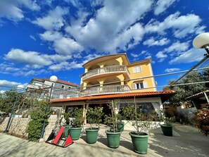 Ein mehrstöckiges Gebäude mit Balkonen, Blumentöpfen und blauem Himmel.