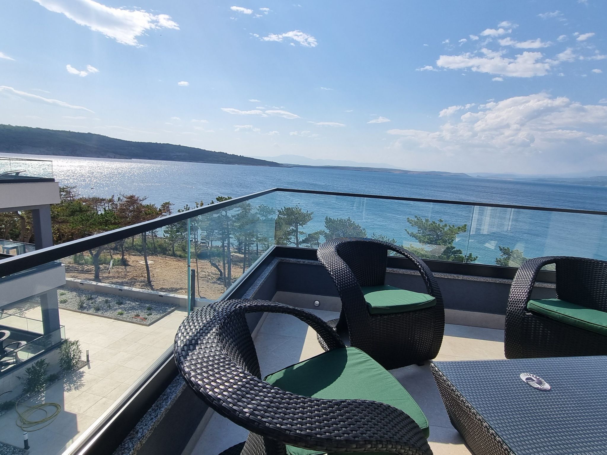 Un balcón con mobiliario de mimbre y vistas a la costa.