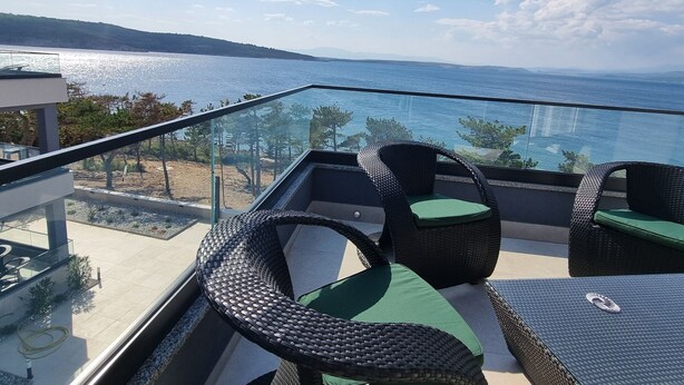 Ein Balkon mit Korbmöbeln und Blick auf die Küste.