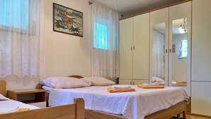 Un dormitorio con dos camas individuales, un armario y un cuadro en la pared.