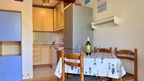 Una cocina compacta con armarios de madera, un refrigerador y una mesa de comedor con sillas.