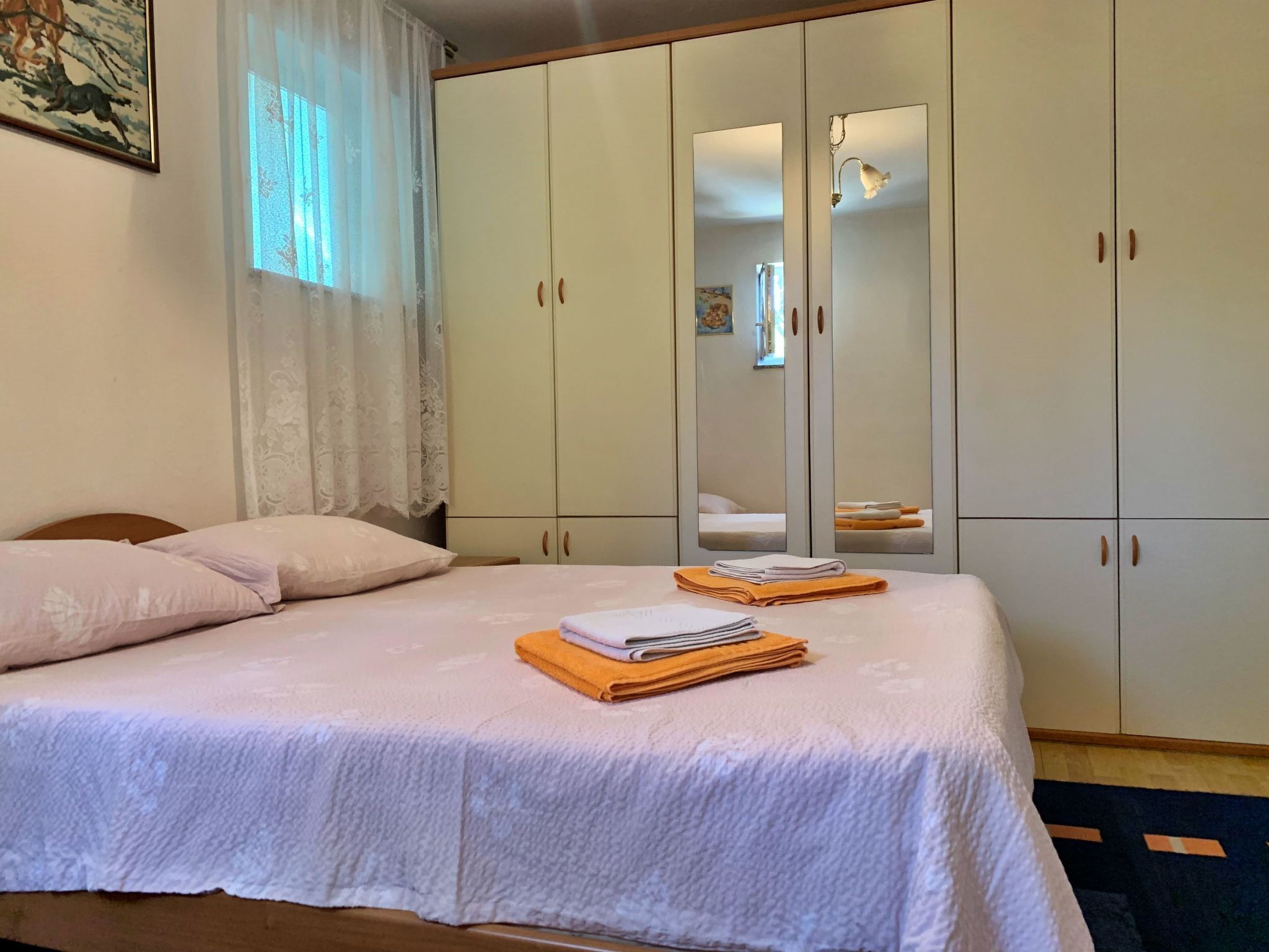 A bedroom with a bed, a wardrobe, and a mirror.