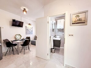 Ein modernes Wohnzimmer mit Essbereich, einem Fernseher und Kunstwerken an den Wänden.